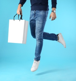 Young man holding paper bag on color background, closeup.  Mockup for design