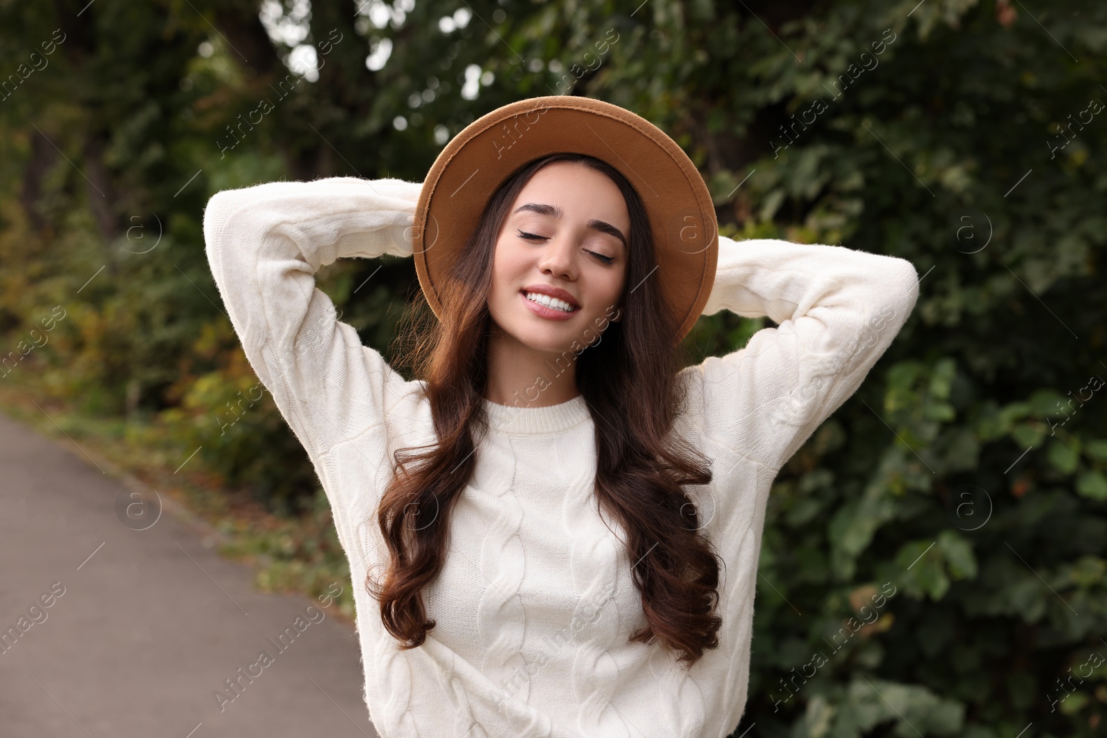 Photo of Beautiful young woman in stylish warm sweater and hat outdoors