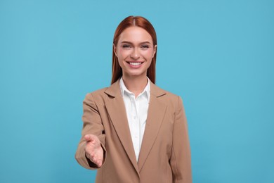 Happy woman welcoming and offering handshake on light blue background