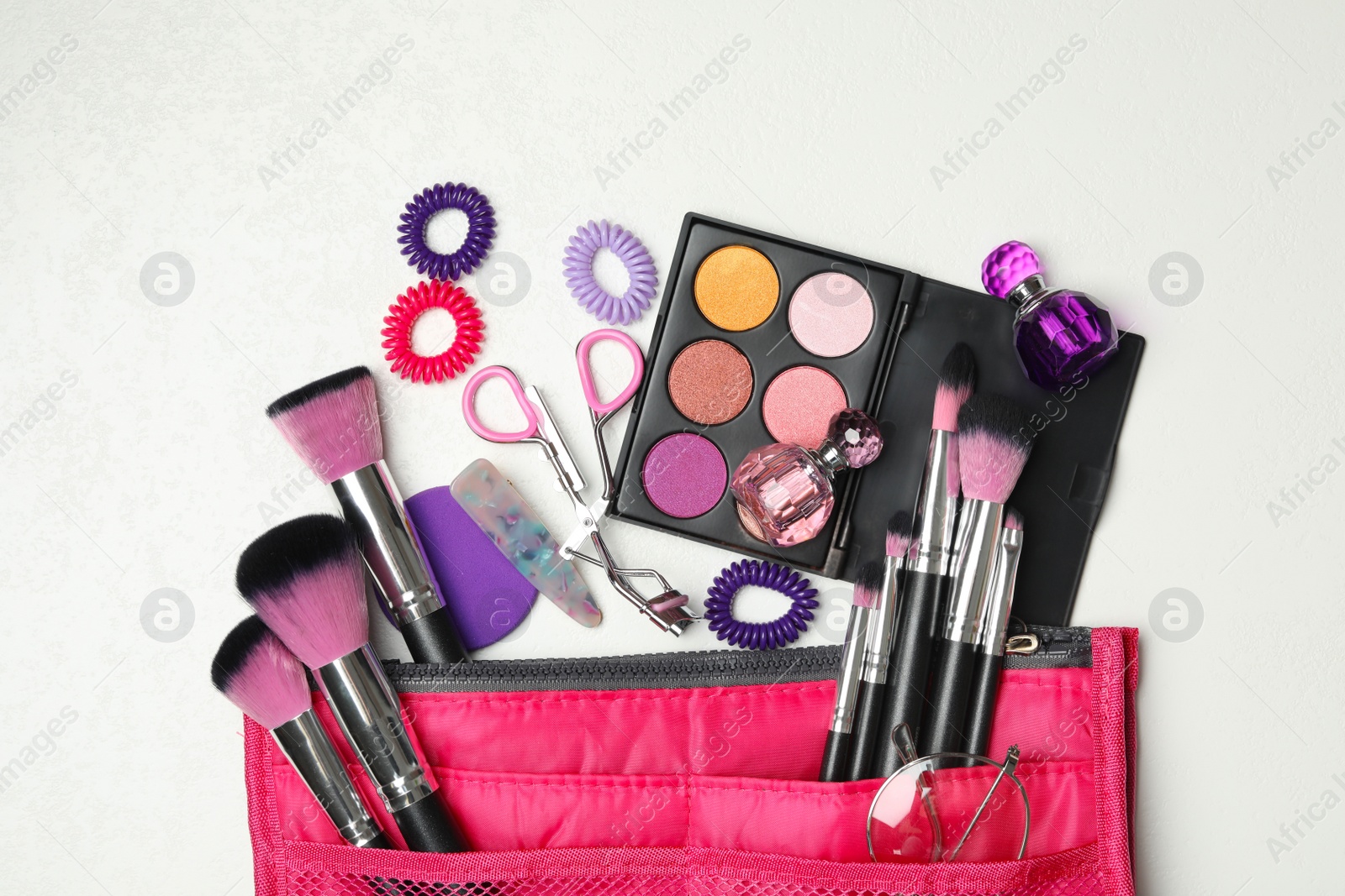 Photo of Cosmetic bag with makeup products and beauty accessories on white background, flat lay