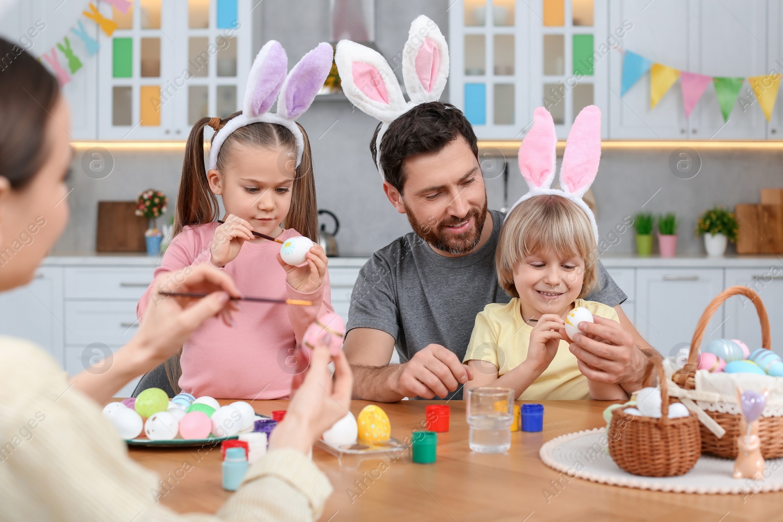 Photo of Happy family painting Easter eggs at table in kitchen