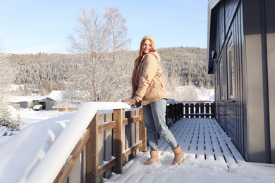 Photo of Happy young woman on terrace outdoors. Winter vacation