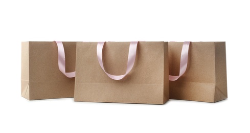 Paper shopping bags with ribbon handles on white background. Mockup for design