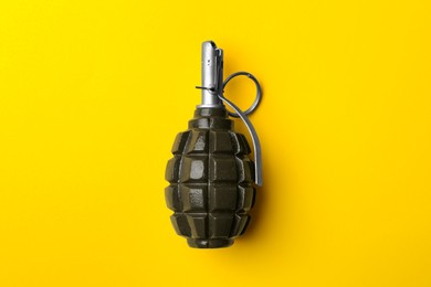 Photo of Hand grenade on yellow background, top view