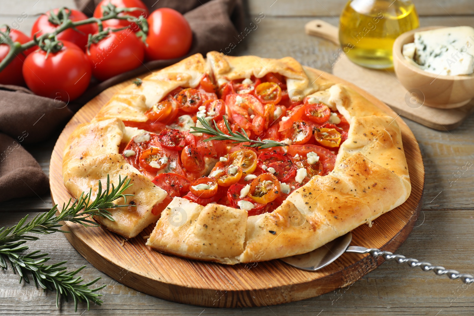 Photo of Tasty galette with tomato, rosemary and cheese (Caprese galette) on wooden table, closeup