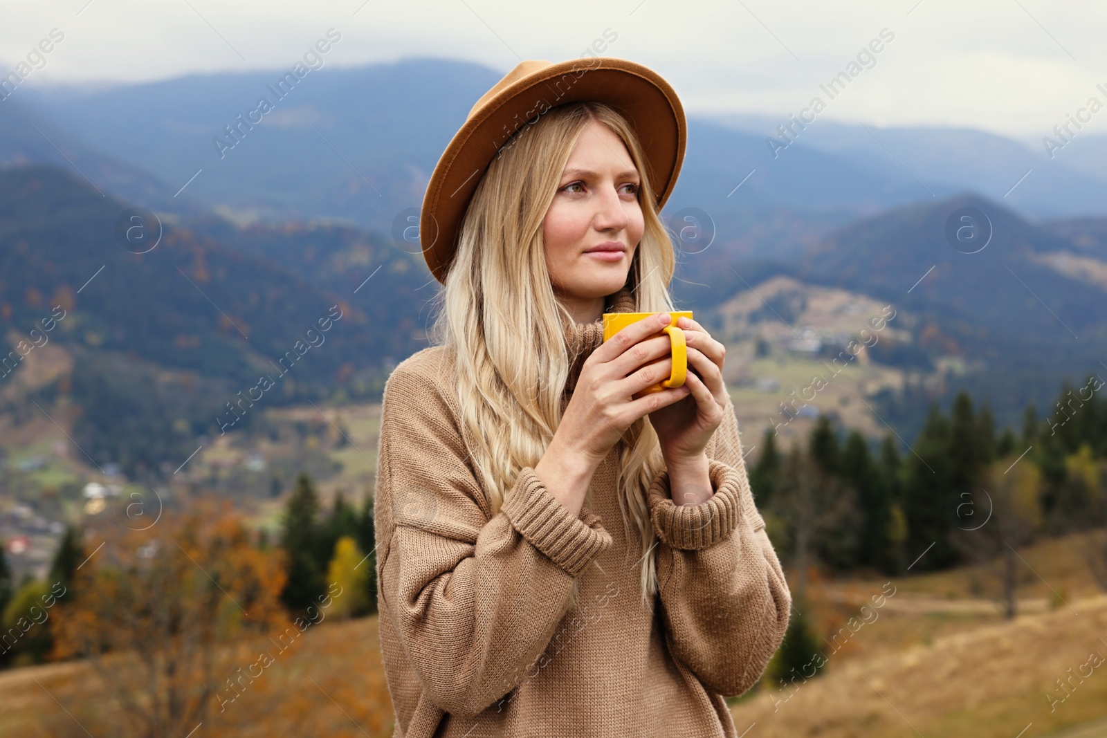 Photo of Young woman with mug of hot drink in mountains. Space for text