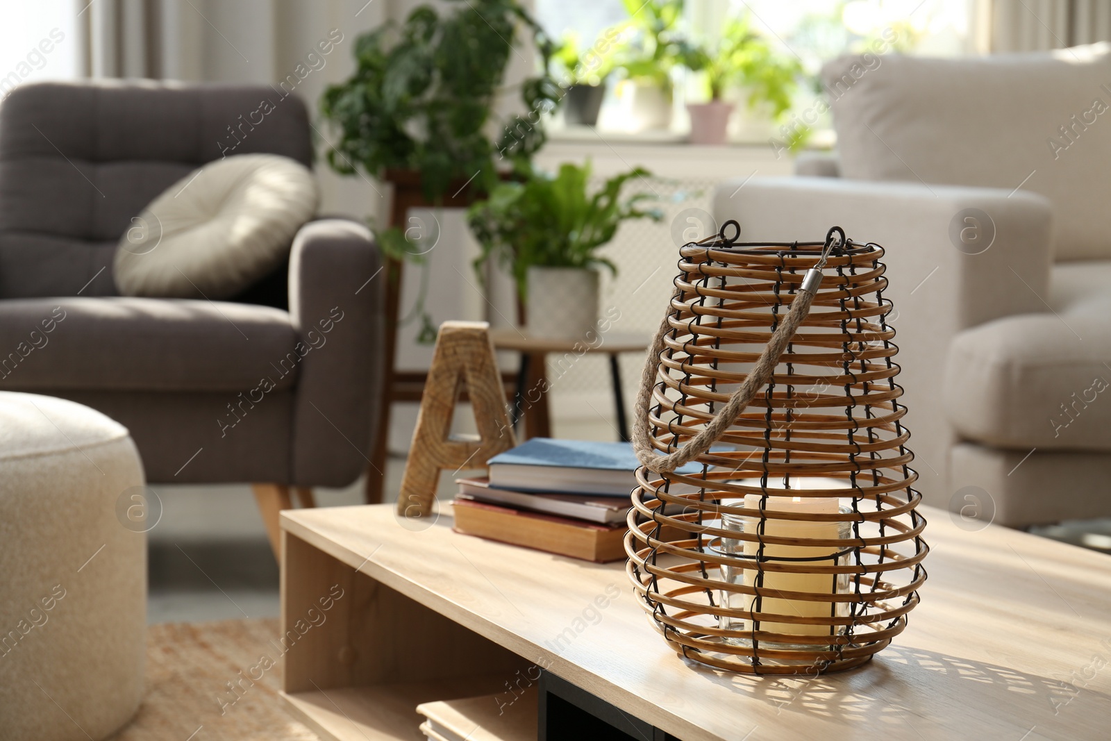 Photo of Stylish holder with burning candle and books on wooden table in living room. Space for text