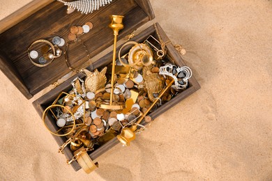 Photo of Open wooden treasure chest on sand, above view. Space for text