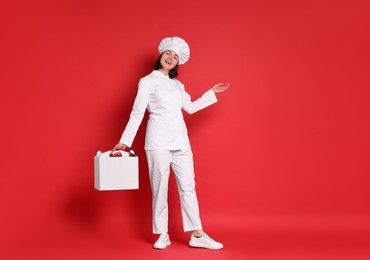Photo of Happy confectioner with cake box on red background
