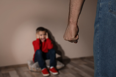 Photo of Man threatening his son indoors, closeup. Domestic violence concept