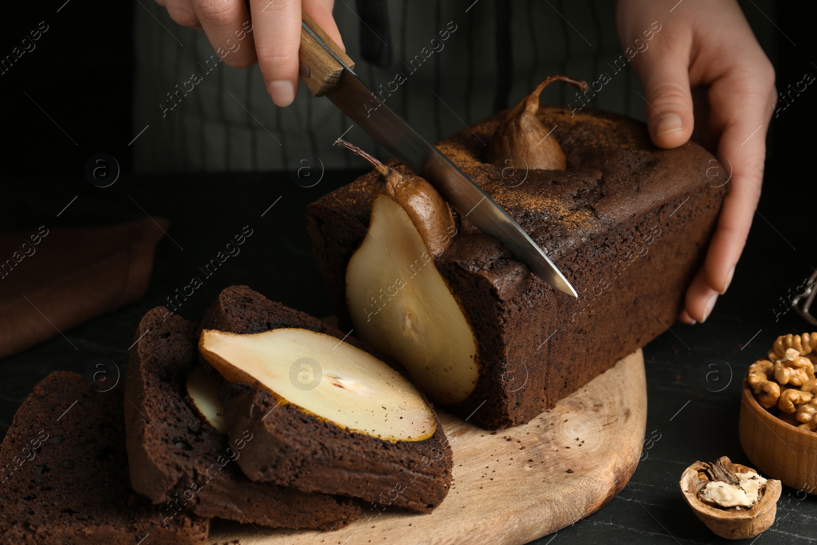 Photo of Woman cutting tasty pear bread at table, closeup. Homemade cake