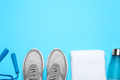 Flat lay composition with man's sneakers and fitness items on light blue background, space for text