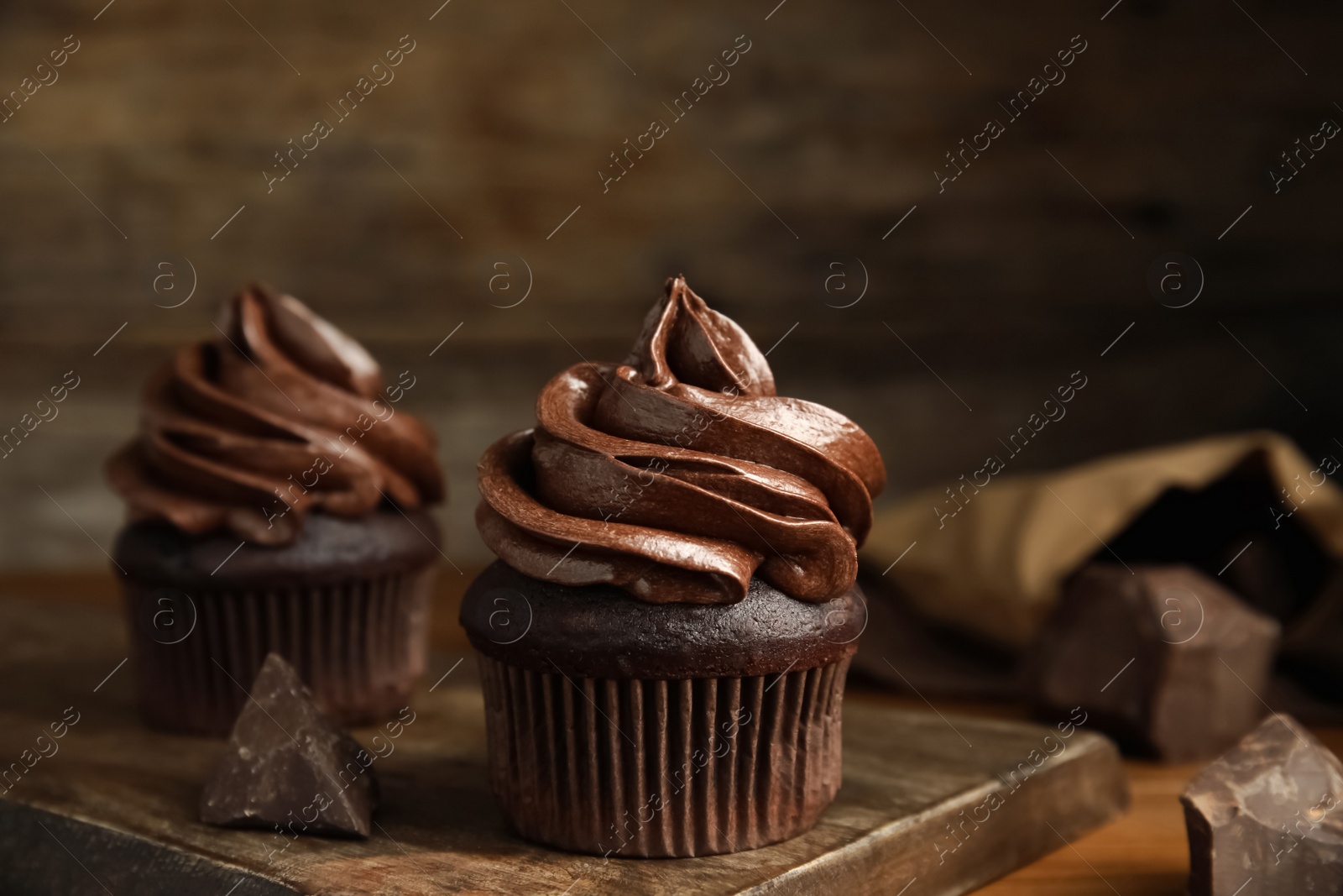 Photo of Delicious chocolate cupcakes with cream on wooden table