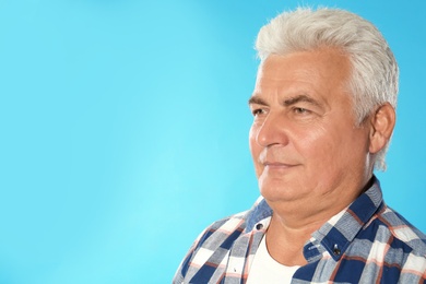 Photo of Mature man with double chin on blue background. Space for text