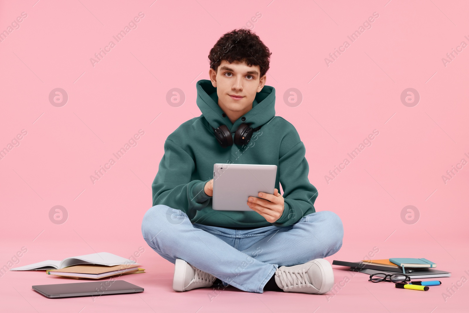 Photo of Portrait of student with tablet and stationery sitting on pink background