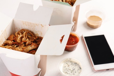 Mobile phone, Chinese noodles and different sauces on white table. Food delivery