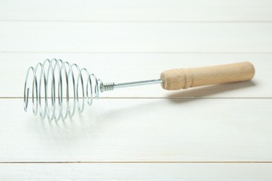 Photo of Metal spring whisk on white wooden table