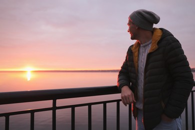 Photo of Man standing near river at sunset, space for text