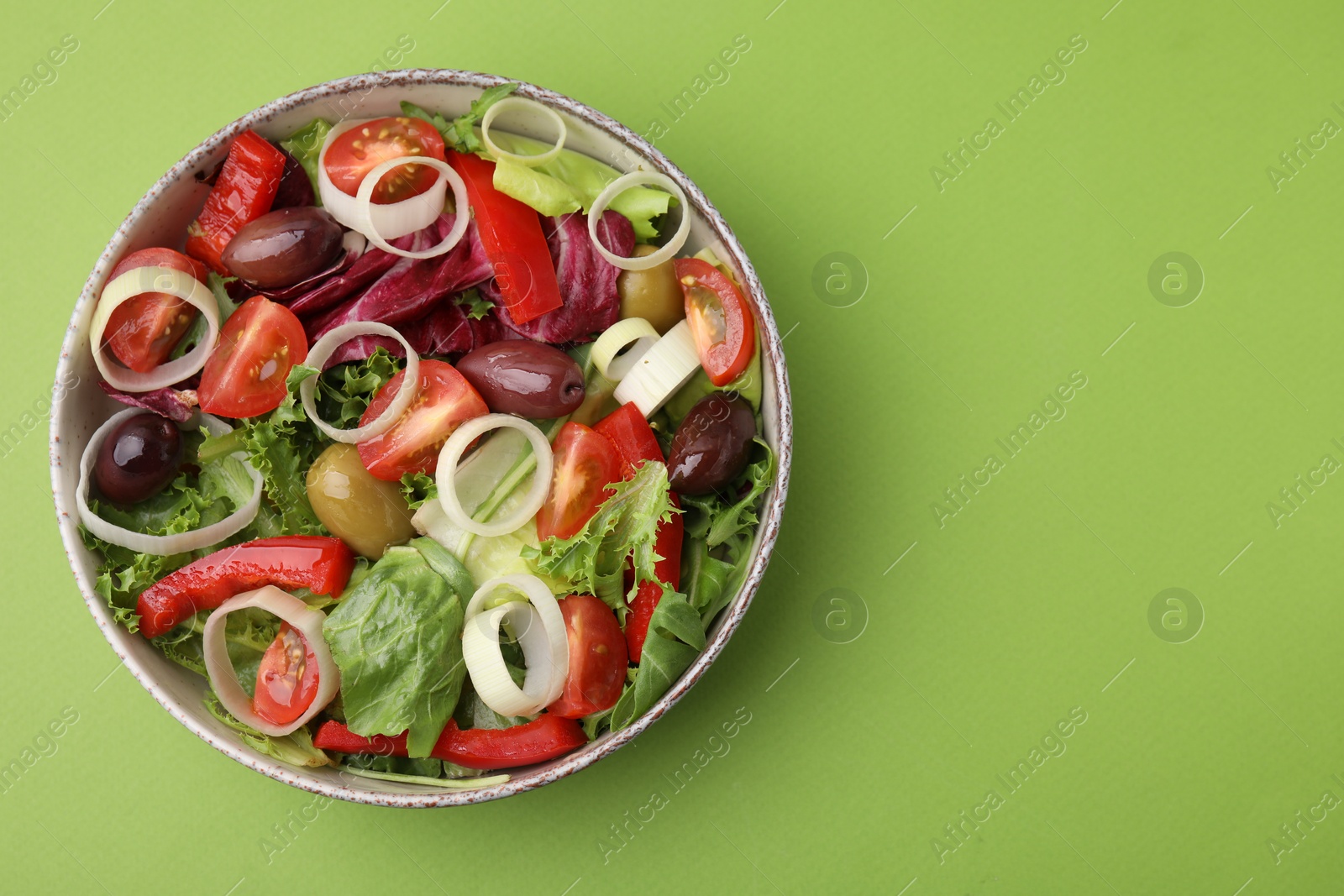 Photo of Bowl of tasty salad with leek and olives on light green table, top view. Space for text