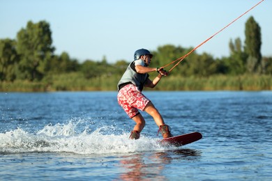 Photo of Teenage boy wakeboarding on river. Extreme water sport