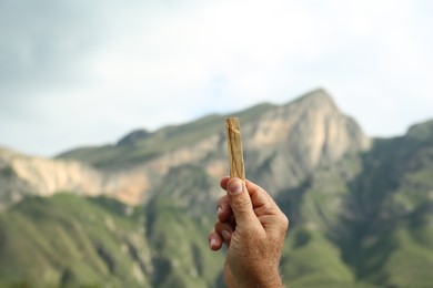 Man holding palo santo stick in high mountains, closeup