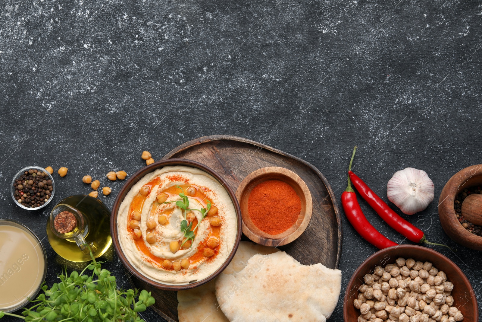 Photo of Delicious hummus with chickpeas and different ingredients on grey textured table, flat lay. Space for text