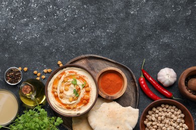 Photo of Delicious hummus with chickpeas and different ingredients on grey textured table, flat lay. Space for text