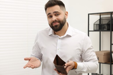 Photo of Upset man with empty wallet in office