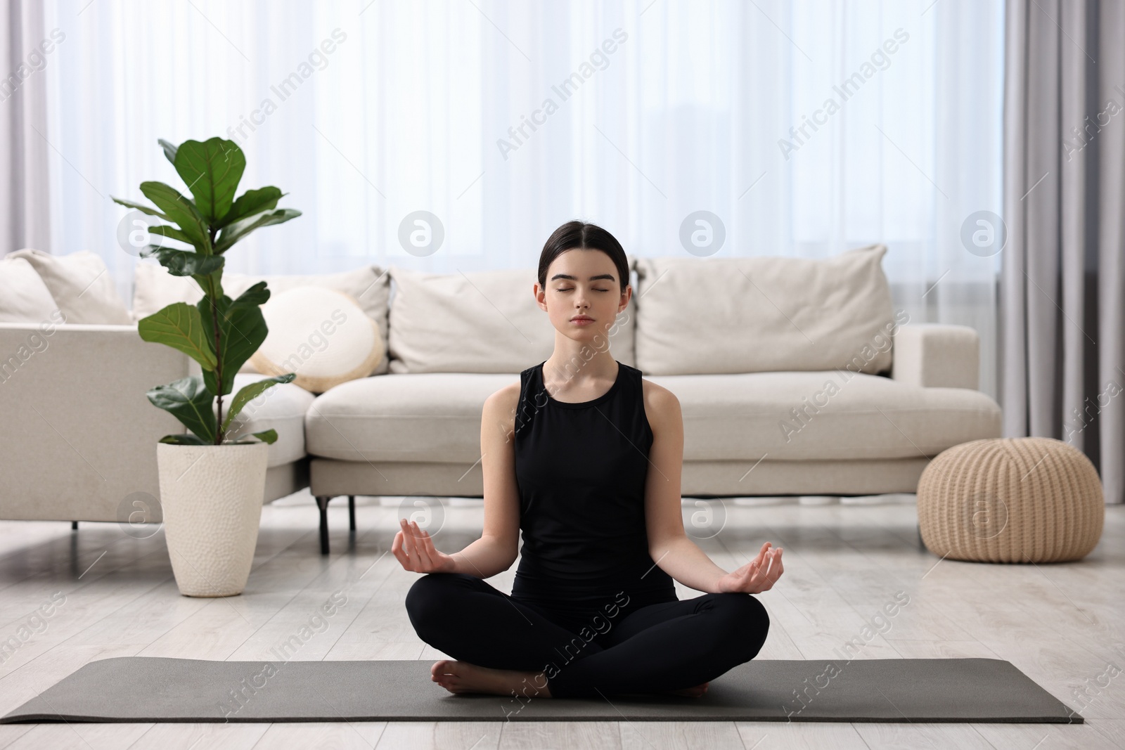 Photo of Beautiful girl meditating on yoga mat at home