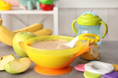 Photo of Bowl with healthy baby food on gray table