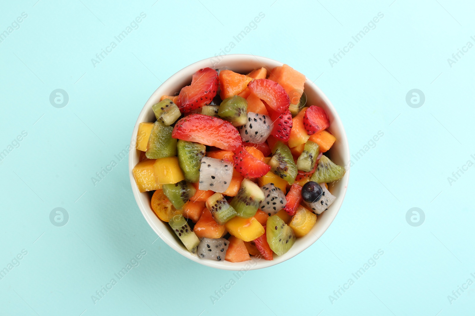 Photo of Delicious exotic fruit salad on turquoise background, top view