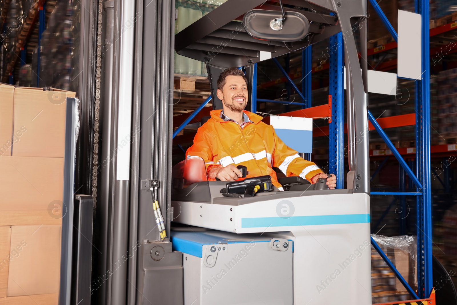 Photo of Happy worker sitting in forklift truck at warehouse