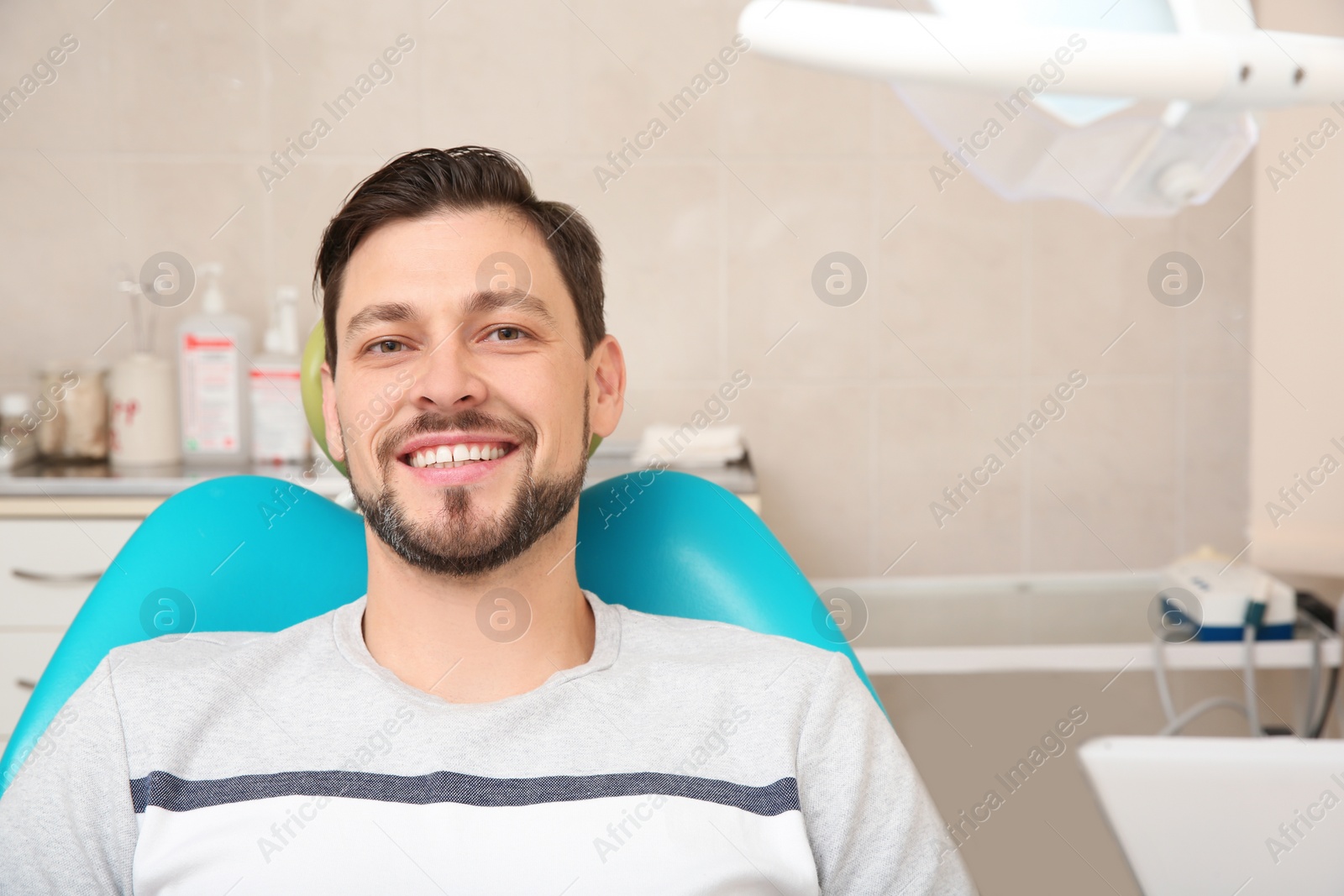 Photo of Happy man having dentist's appointment in modern clinic. Space for text
