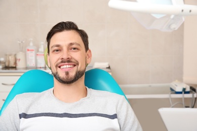 Photo of Happy man having dentist's appointment in modern clinic. Space for text