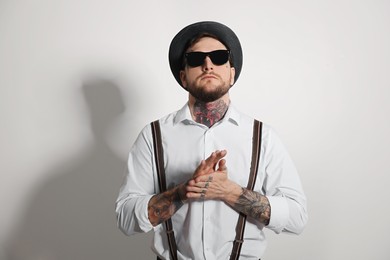 Photo of Handsome hipster man wearing stylish sunglasses on light grey background