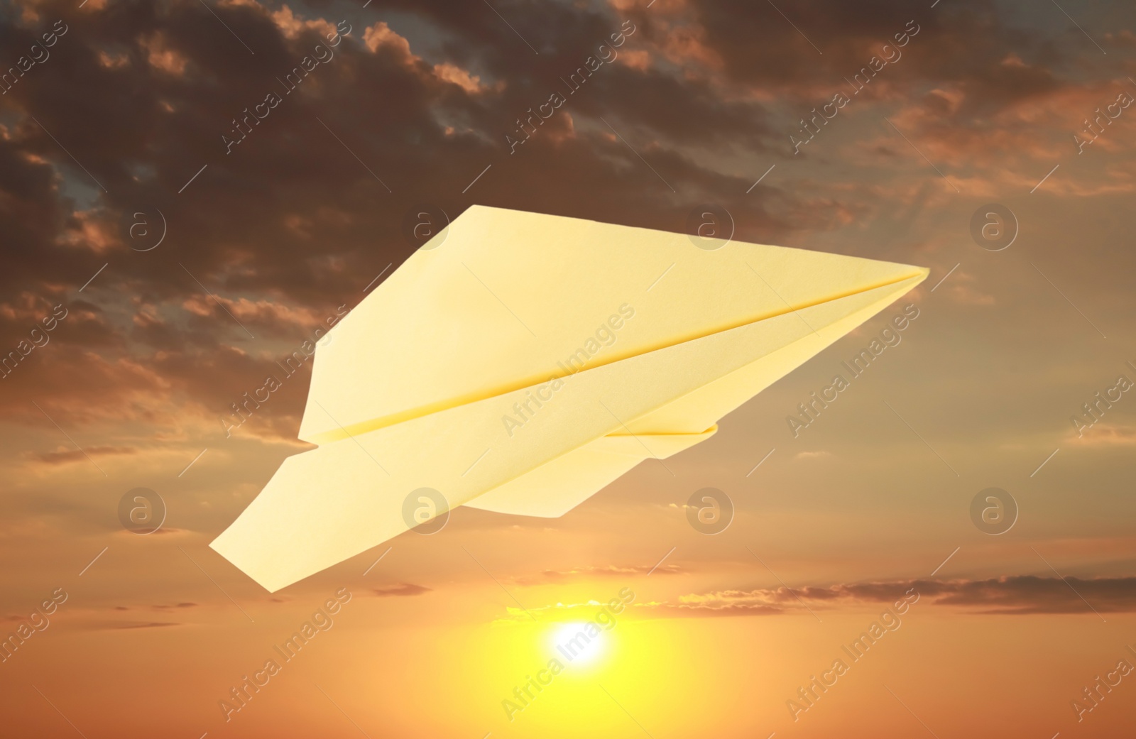 Image of Yellow paper plane and view of beautiful sky at sunset