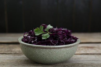 Photo of Tasty red cabbage sauerkraut with parsley on wooden table