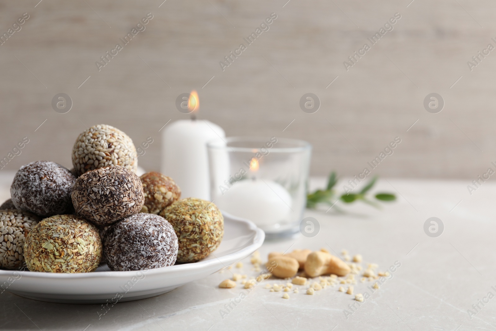 Photo of Different delicious vegan candy balls on light grey marble table. Space for text