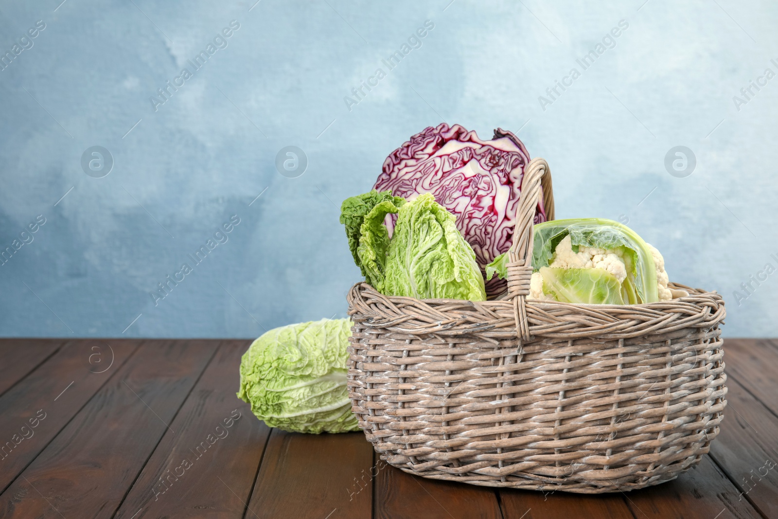 Photo of Basket with tasty cabbages on wooden table