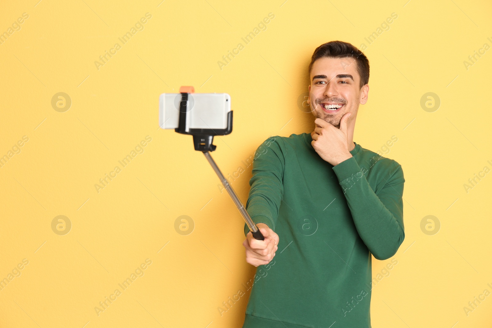 Photo of Young handsome man taking selfie against color background