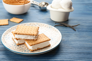 Photo of Sweet delicious ice cream cookie sandwiches on blue wooden table