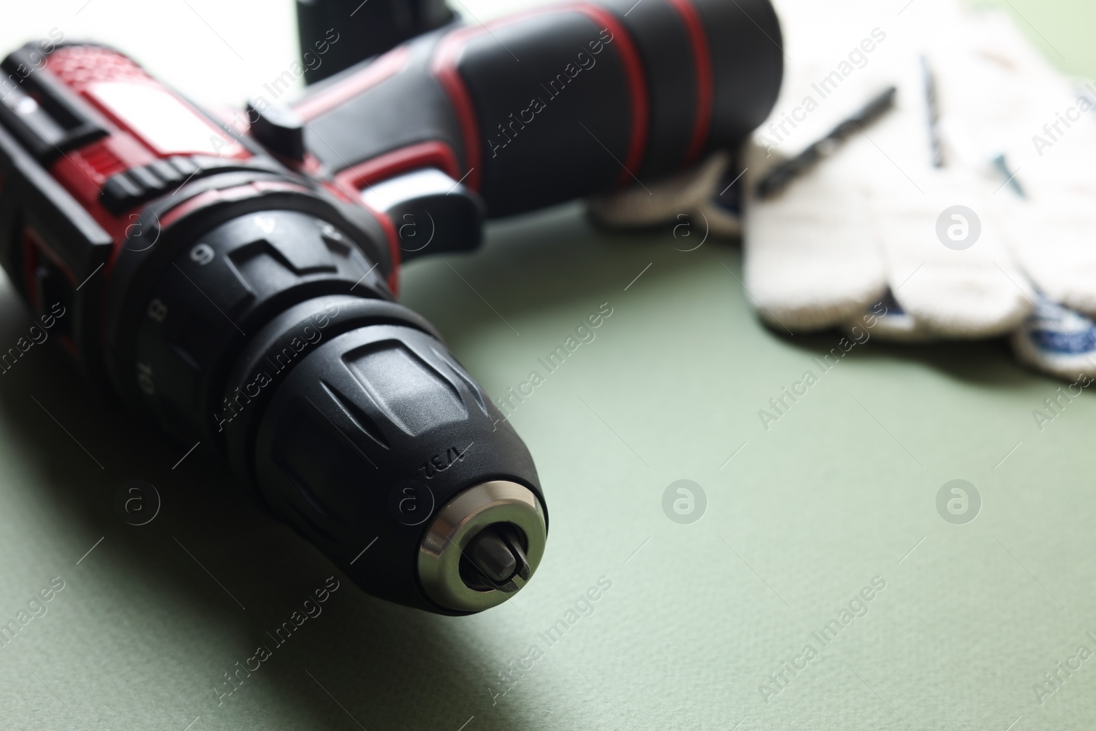 Photo of Electric screwdriver on pale green background, closeup. Space for text