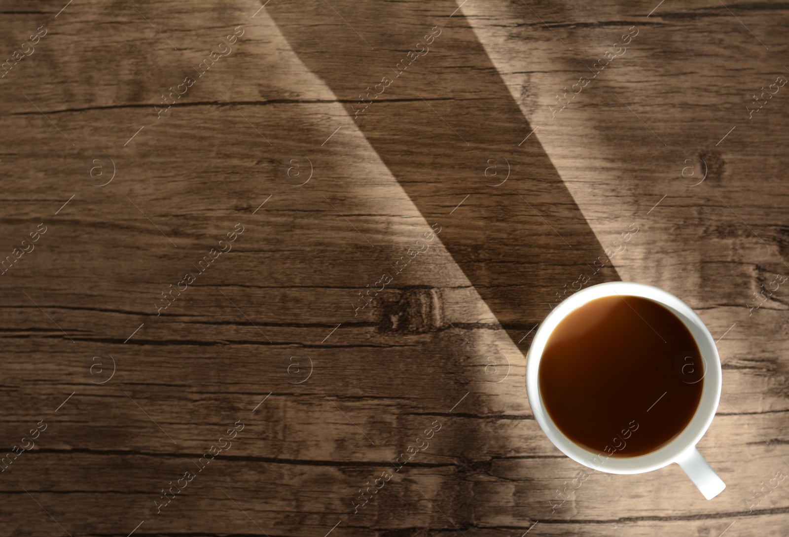 Photo of Cup of coffee on wooden table in morning, top view. Space for text