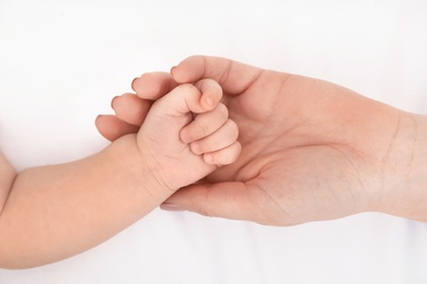 Photo of Mother holding her baby's hand on bed, top view