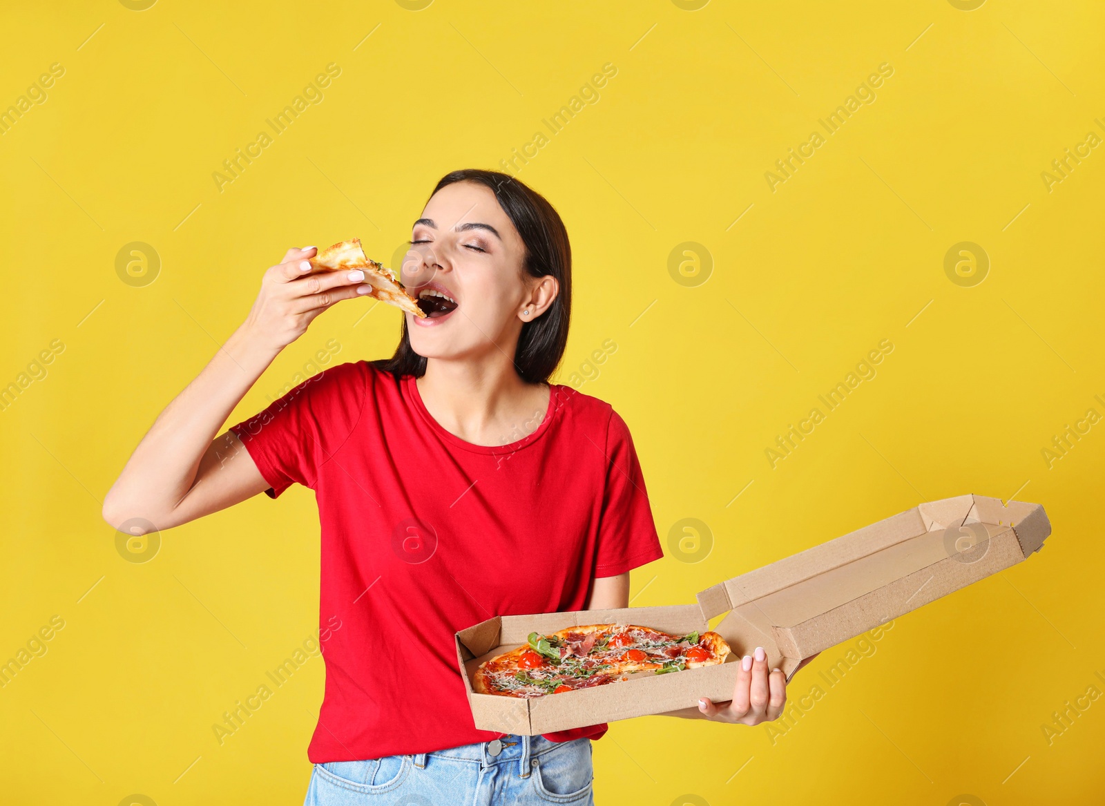 Photo of Beautiful woman eating tasty pizza on yellow background