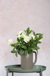 Vase with bouquet of beautiful flowers on table against color background. Space for text