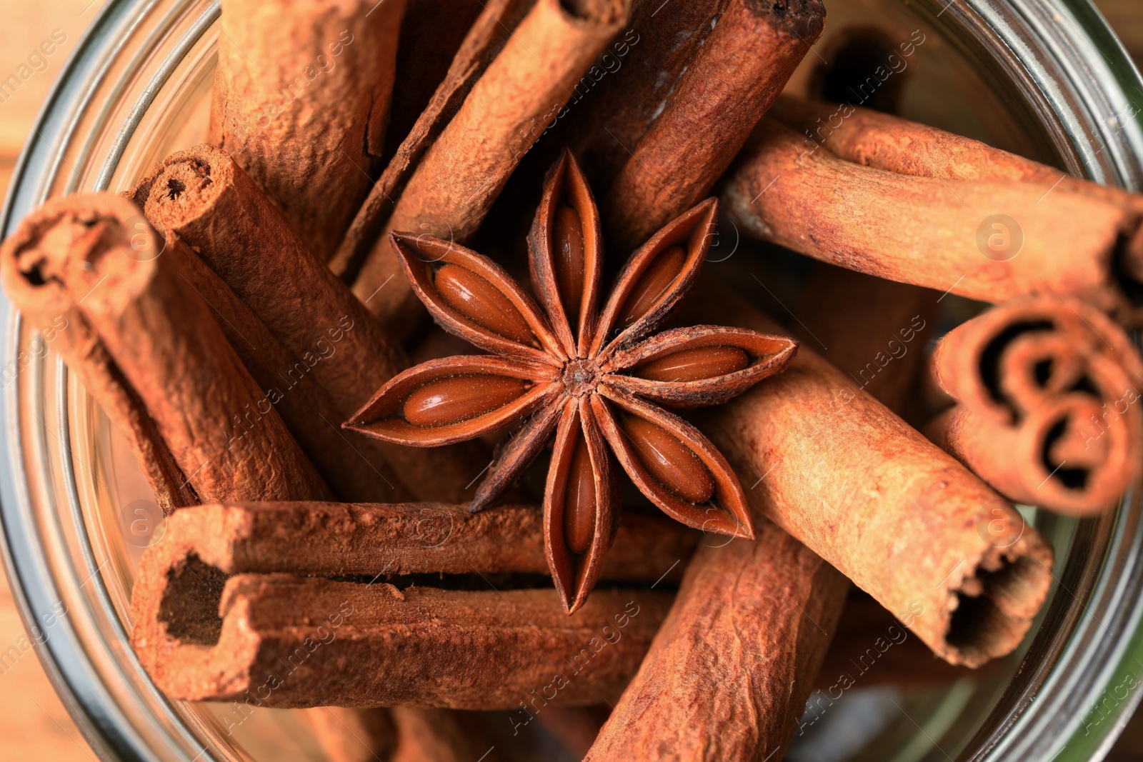 Photo of Bowl with aromatic cinnamon sticks and anise star on table, closeup