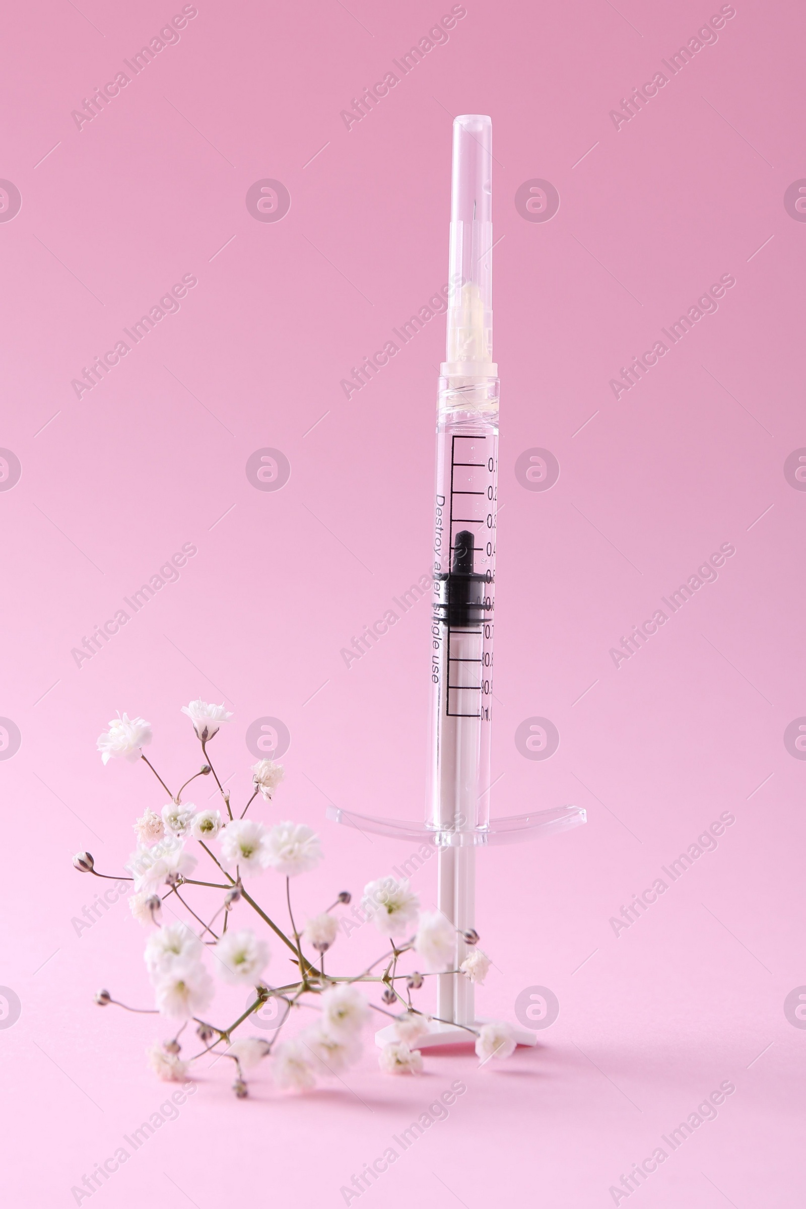 Photo of Cosmetology. Medical syringe and gypsophila on pink background