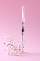 Photo of Cosmetology. Medical syringe and gypsophila on pink background
