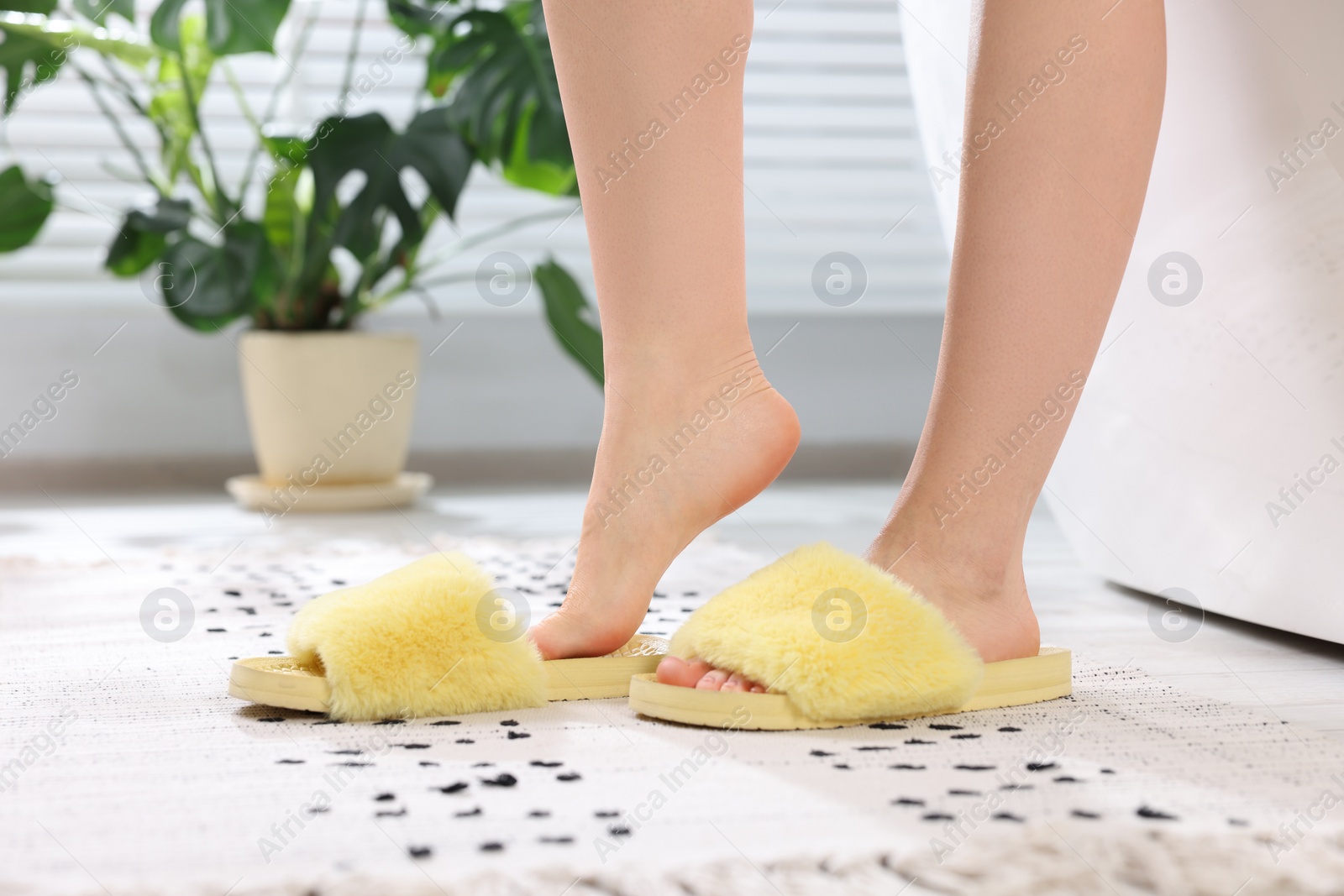 Photo of Woman in yellow soft slippers at home, closeup